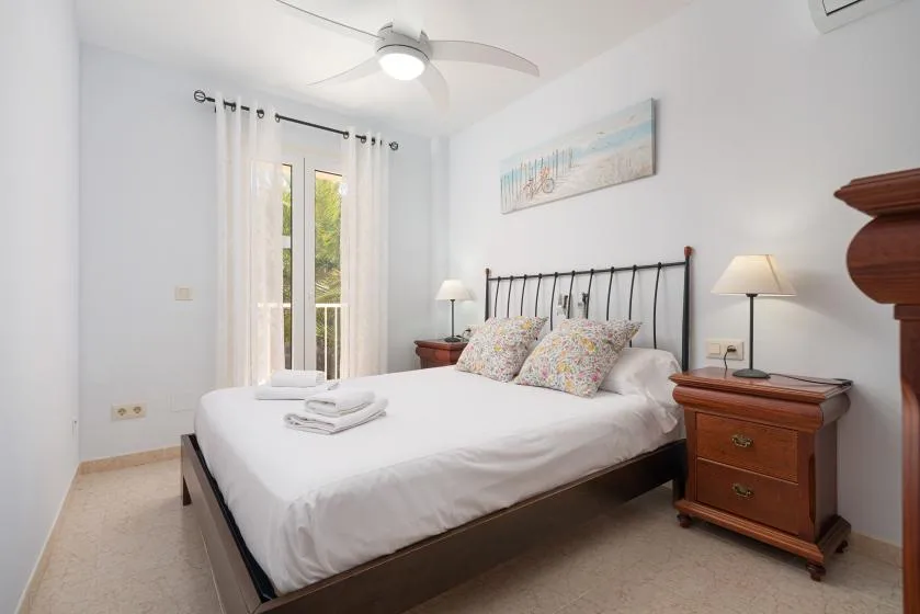 Un dormitorio luminoso con una cama bien tendida y mesitas de noche a ambos lados.