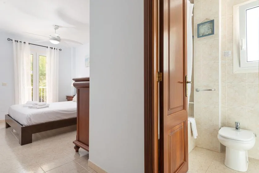 Un dormitorio con una cama junto a una puerta abierta hacia un baño.
