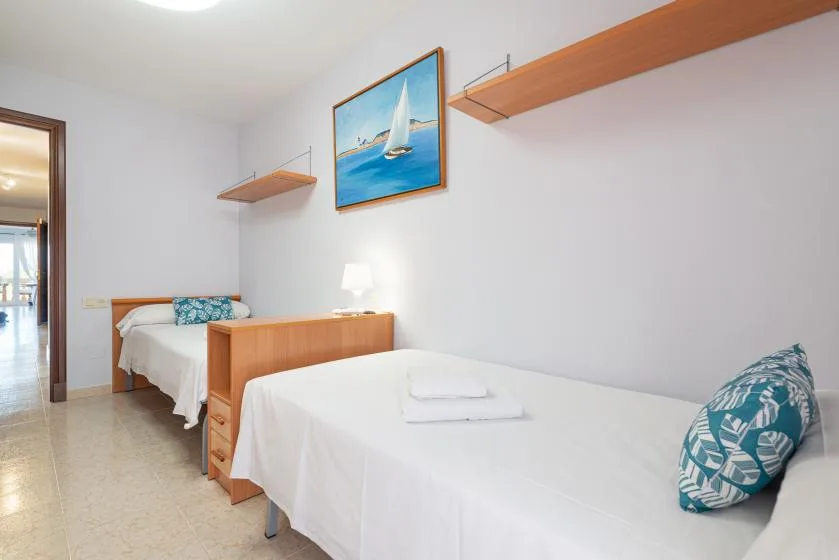 Un dormitorio con dos camas individuales, ropa de cama blanca y un cuadro de un velero.