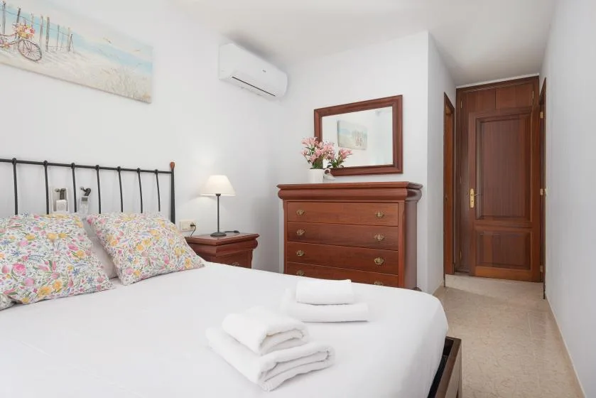 Un dormitorio con una cama, toallas dobladas y una cómoda de madera.