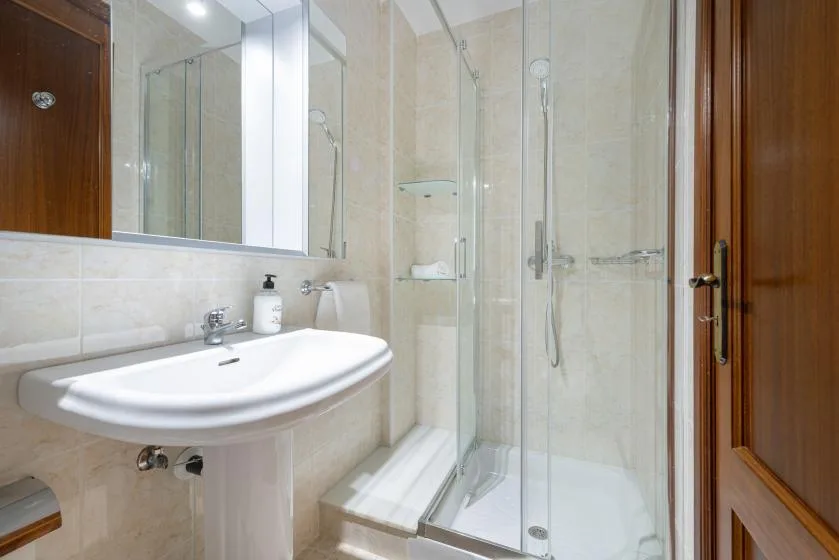 Un baño con azulejos, lavabo y ducha de vidrio.