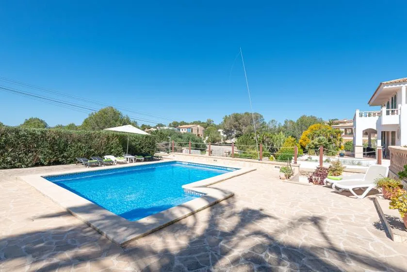 Una piscina al aire libre ocupa un patio pavimentado junto a un edificio.