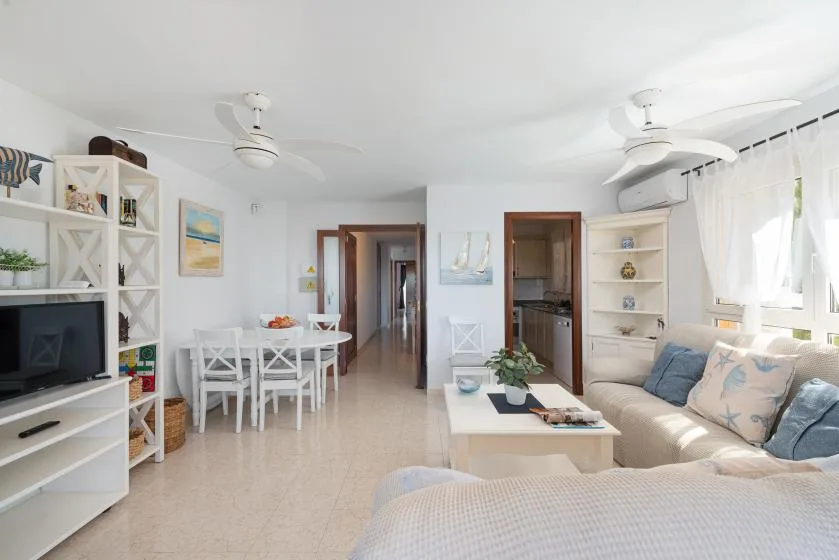 Una luminosa sala de estar y comedor con sofá, mesa de comedor y ventanas grandes.