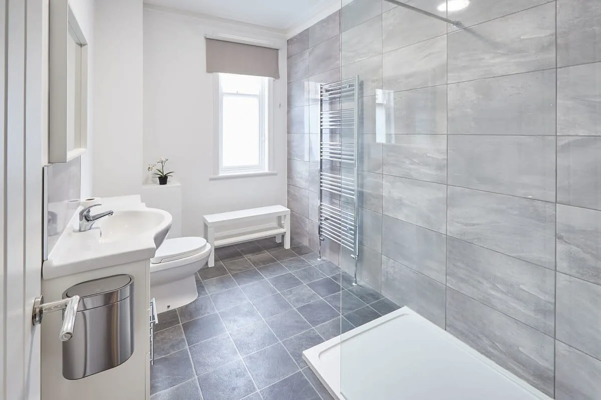 A bright bathroom with a sink, toilet, and glass shower area.