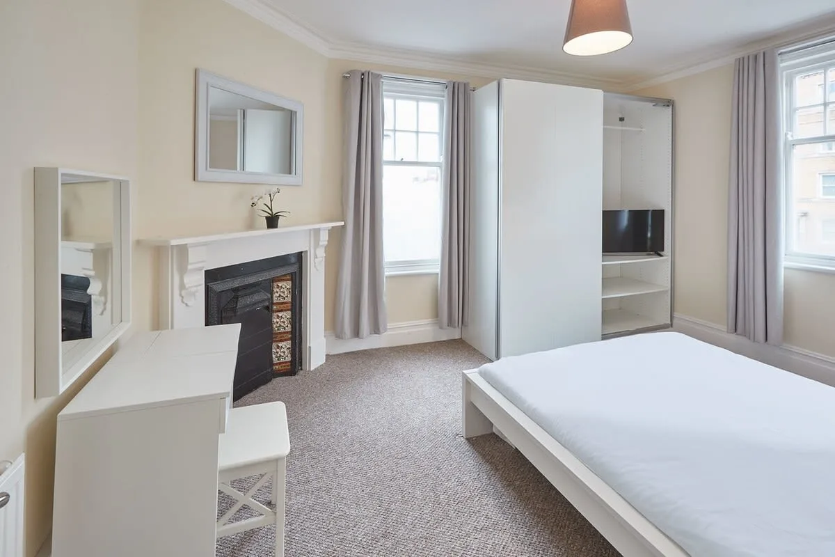 A bedroom with a bed, a fireplace, and a built-in television cabinet.