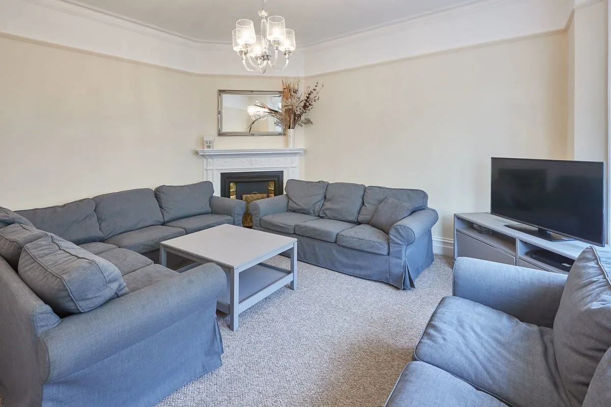 A living room with gray seating, a coffee table, and a television.