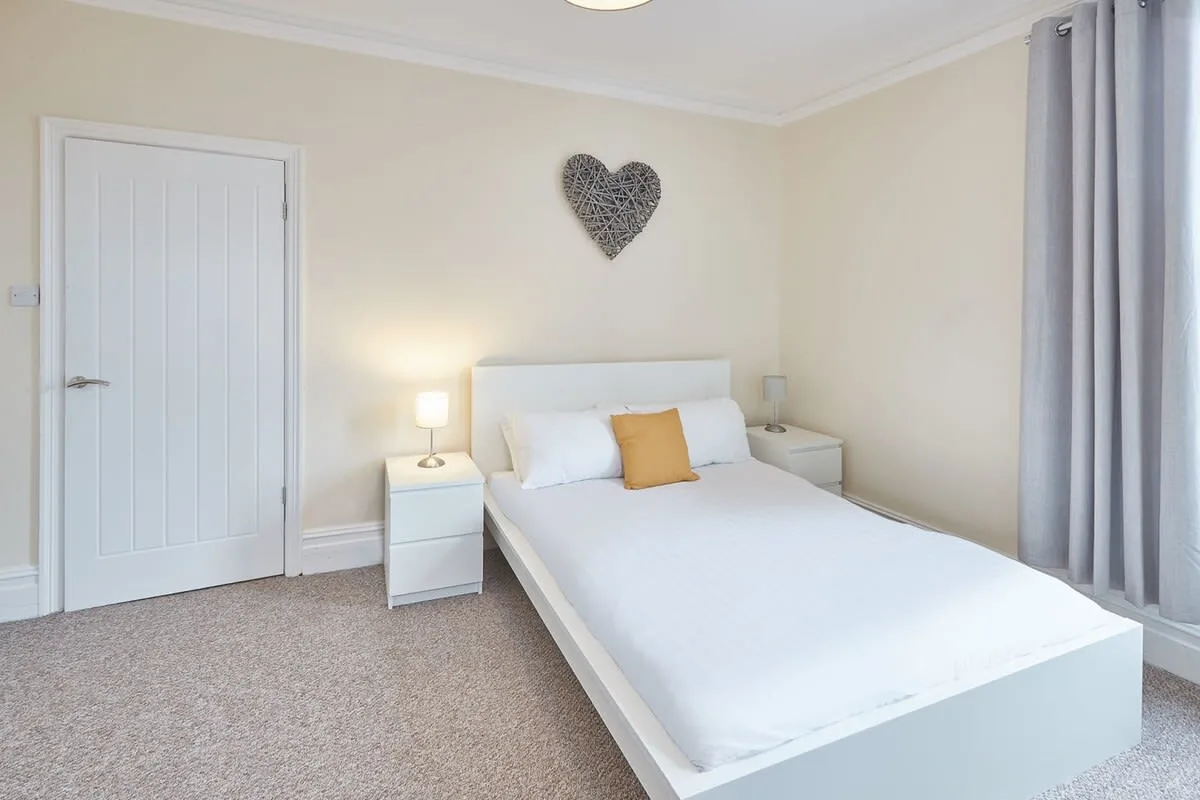 A bedroom with a bed, bedside tables, and curtains.