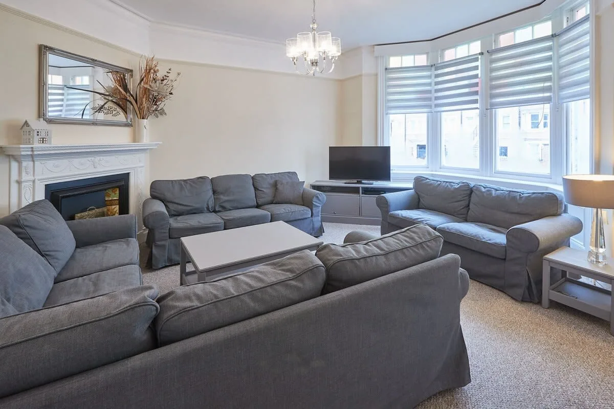 A bright living room with gray seating arranged around a coffee table.