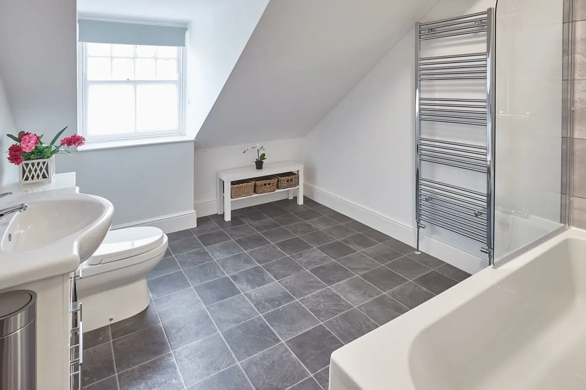 A bathroom with a bathtub, sink, and sloped ceiling.