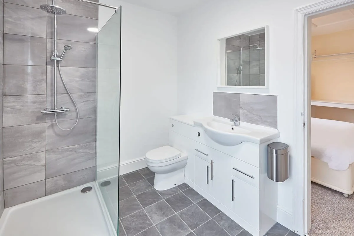 A bathroom with a glass shower, toilet, and sink vanity.