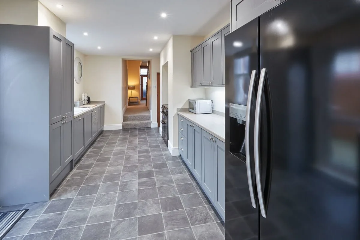 A modern kitchen with gray cabinets and a large refrigerator.