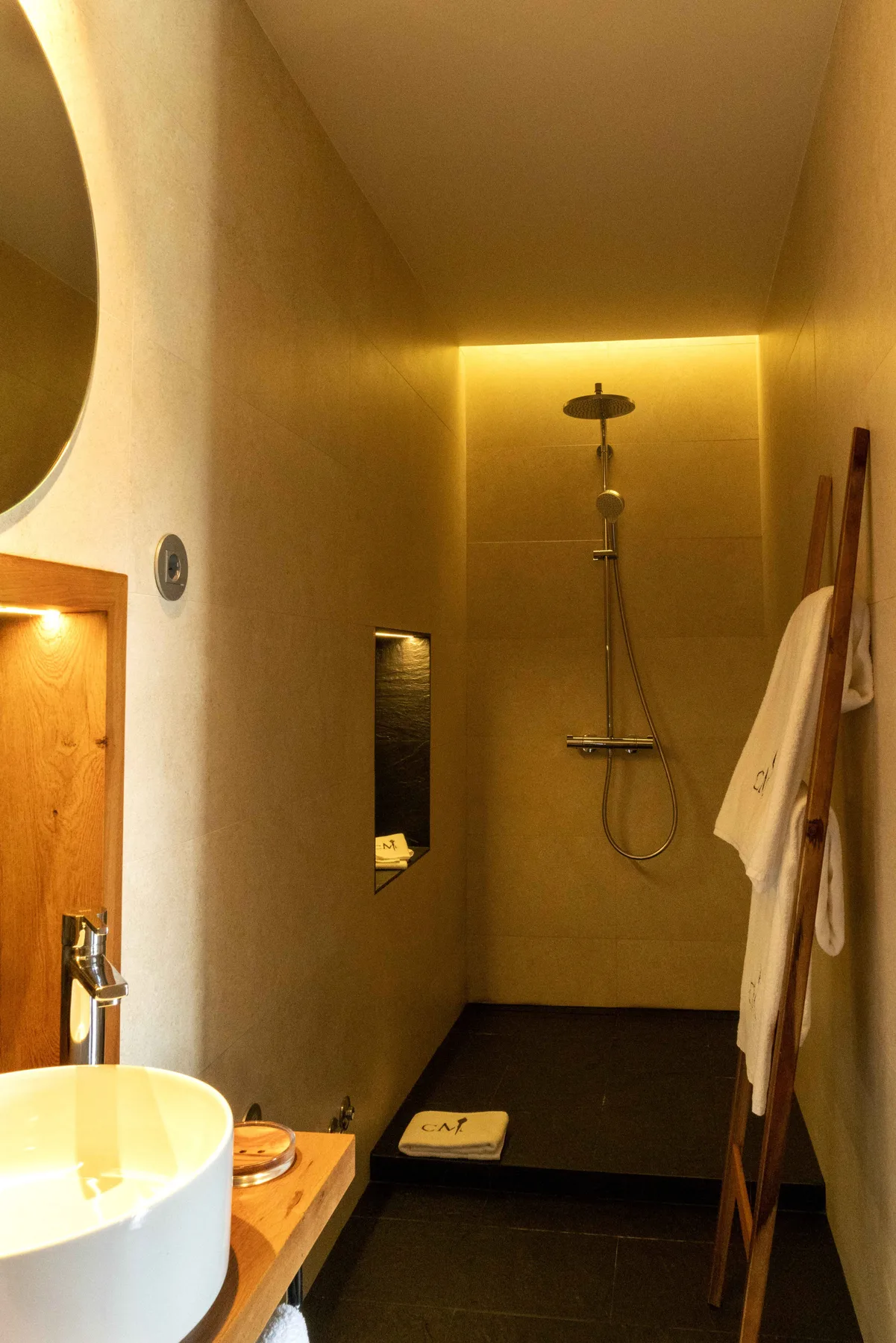 Un baño con un lavabo en primer plano y una ducha al fondo.