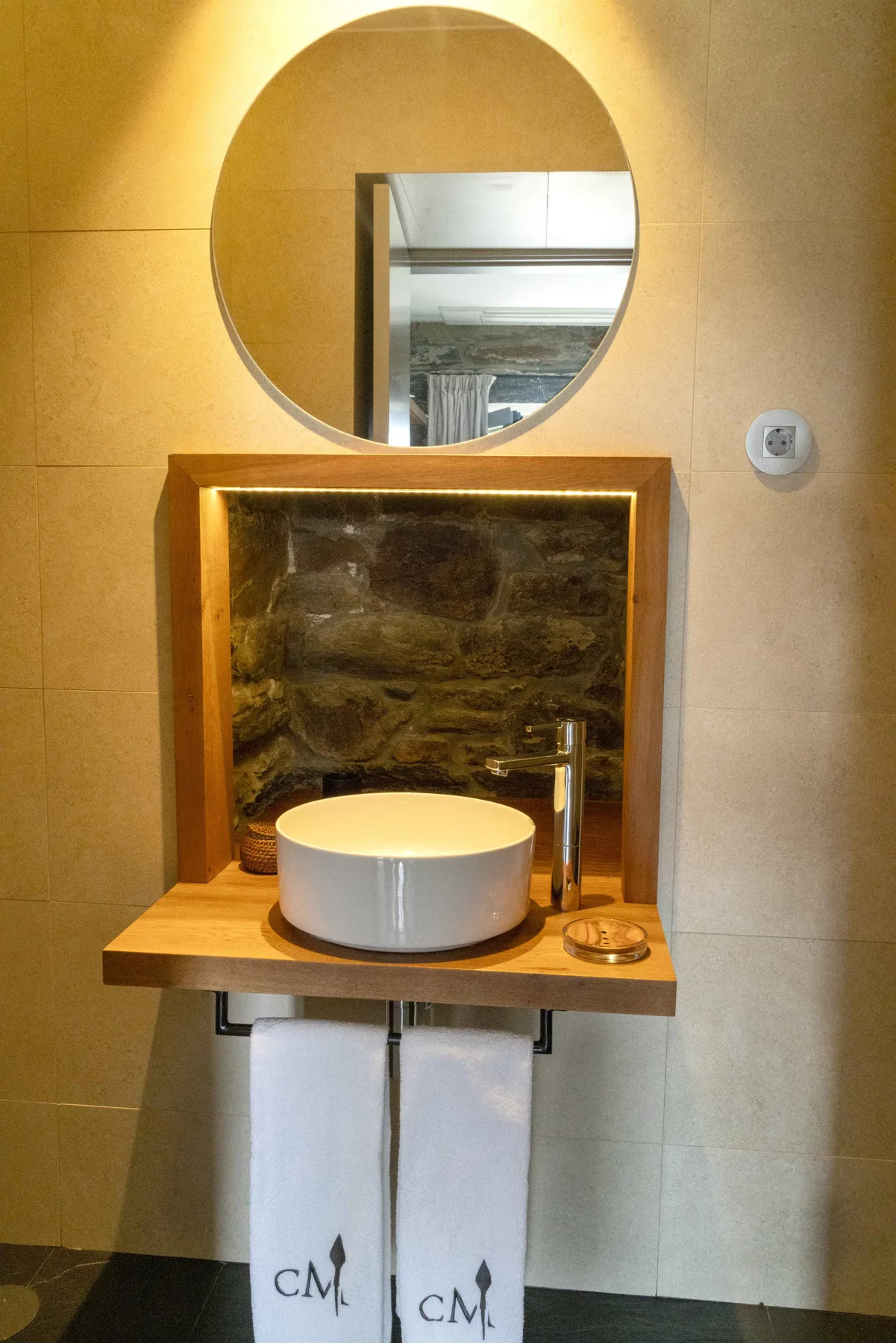 Un lavabo de baño con un espejo redondo y una pila blanca.