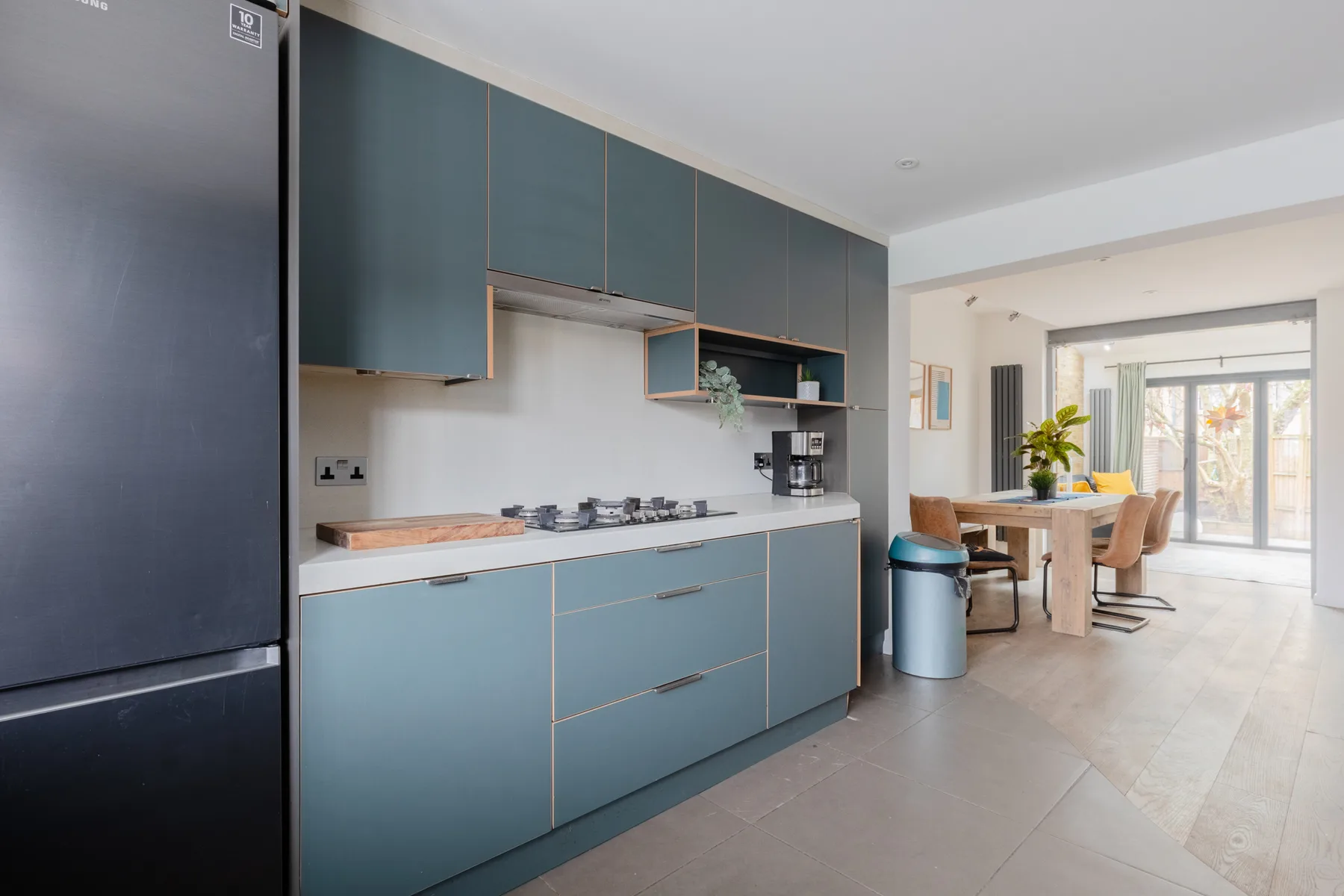 Una cocina moderna se abre a un comedor con mesa y sillas.