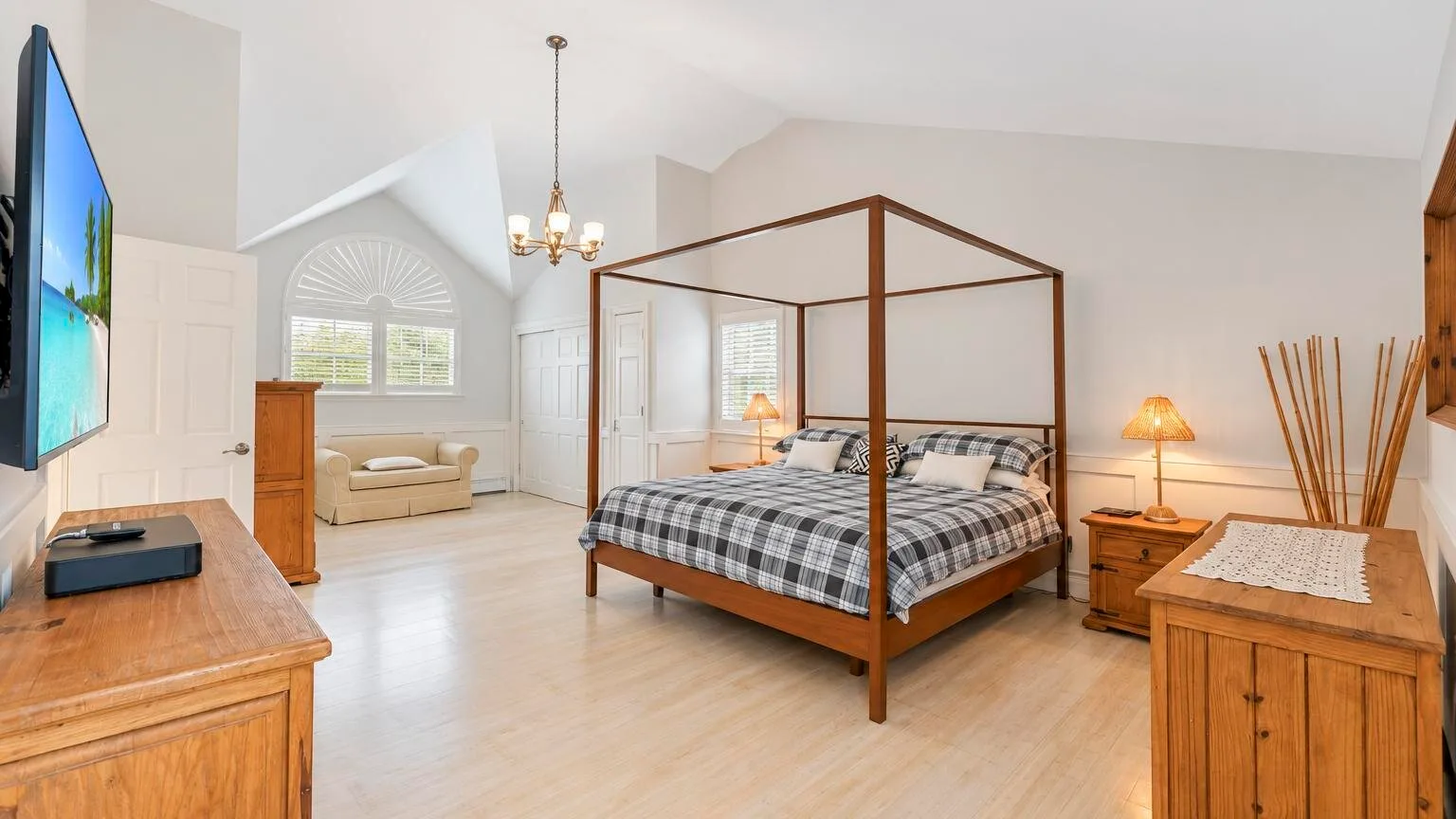 Un dormitorio luminoso cuenta con una cama con dosel y una gran ventana arqueada.
