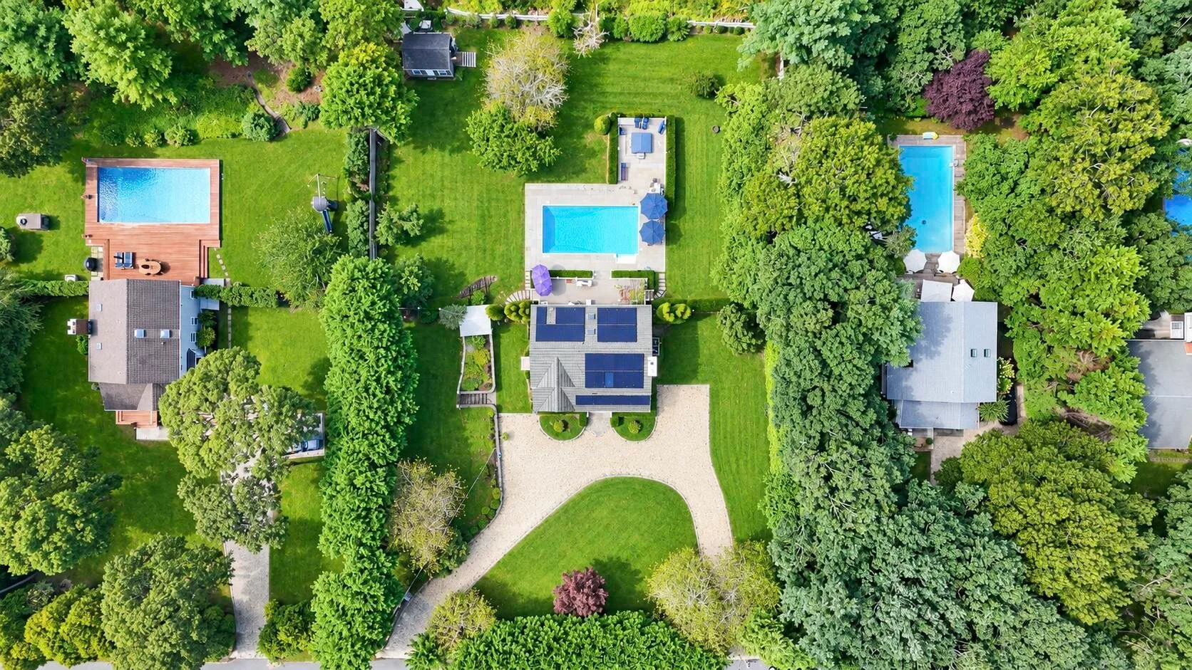 Vista aérea de una propiedad ajardinada con varias casas, piscinas y jardines.