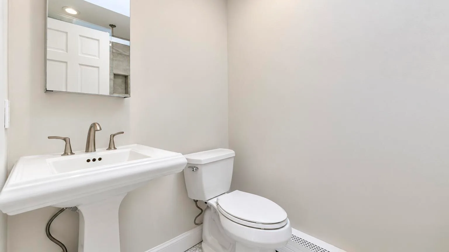 Un baño con lavabo de pedestal e inodoro.