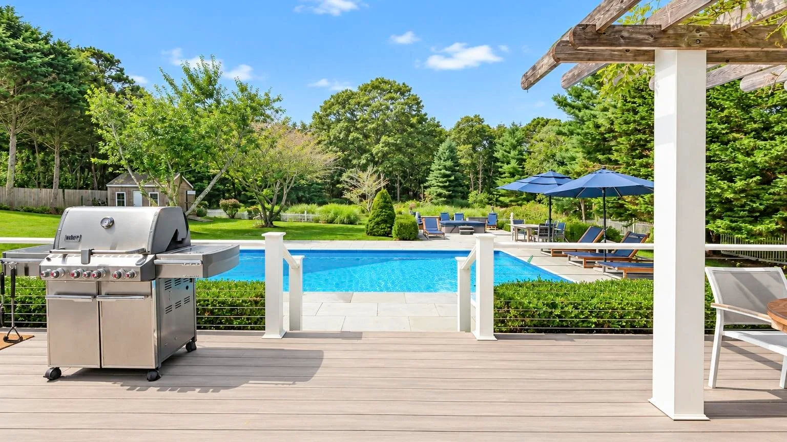 Una terraza trasera da a una piscina y un jardín, con una parrilla cerca.