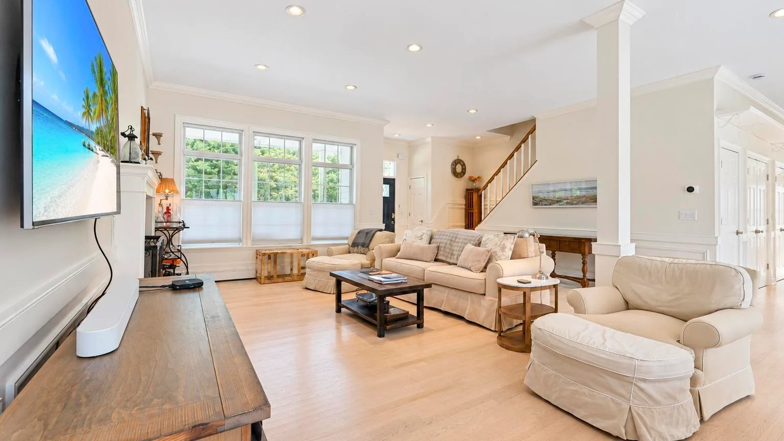 Una sala luminosa con asientos beige, una mesa de centro y grandes ventanas.