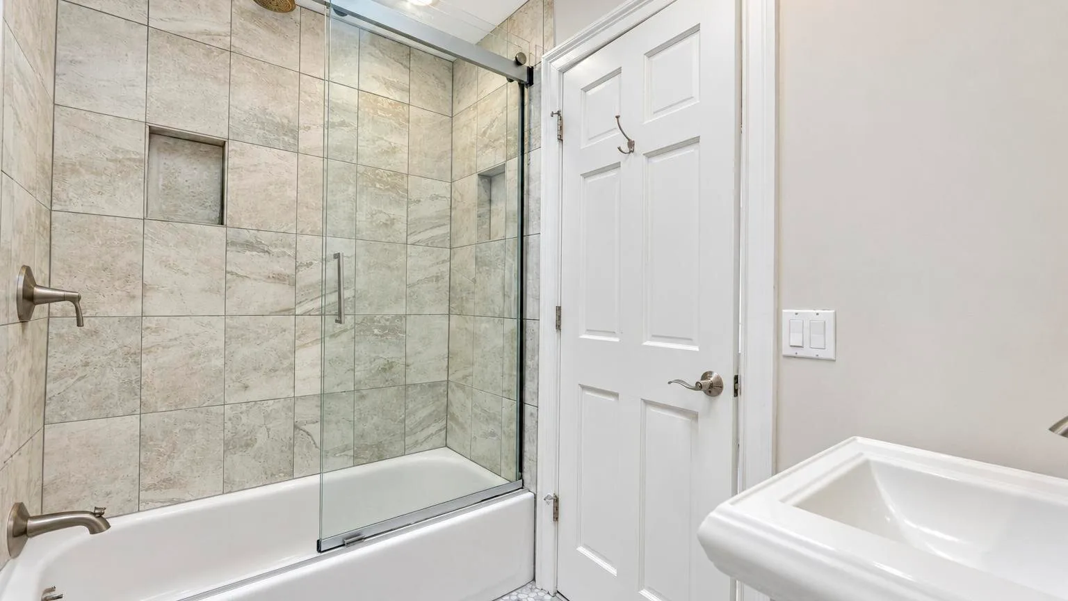 Un baño con una ducha de vidrio y un lavabo blanco.