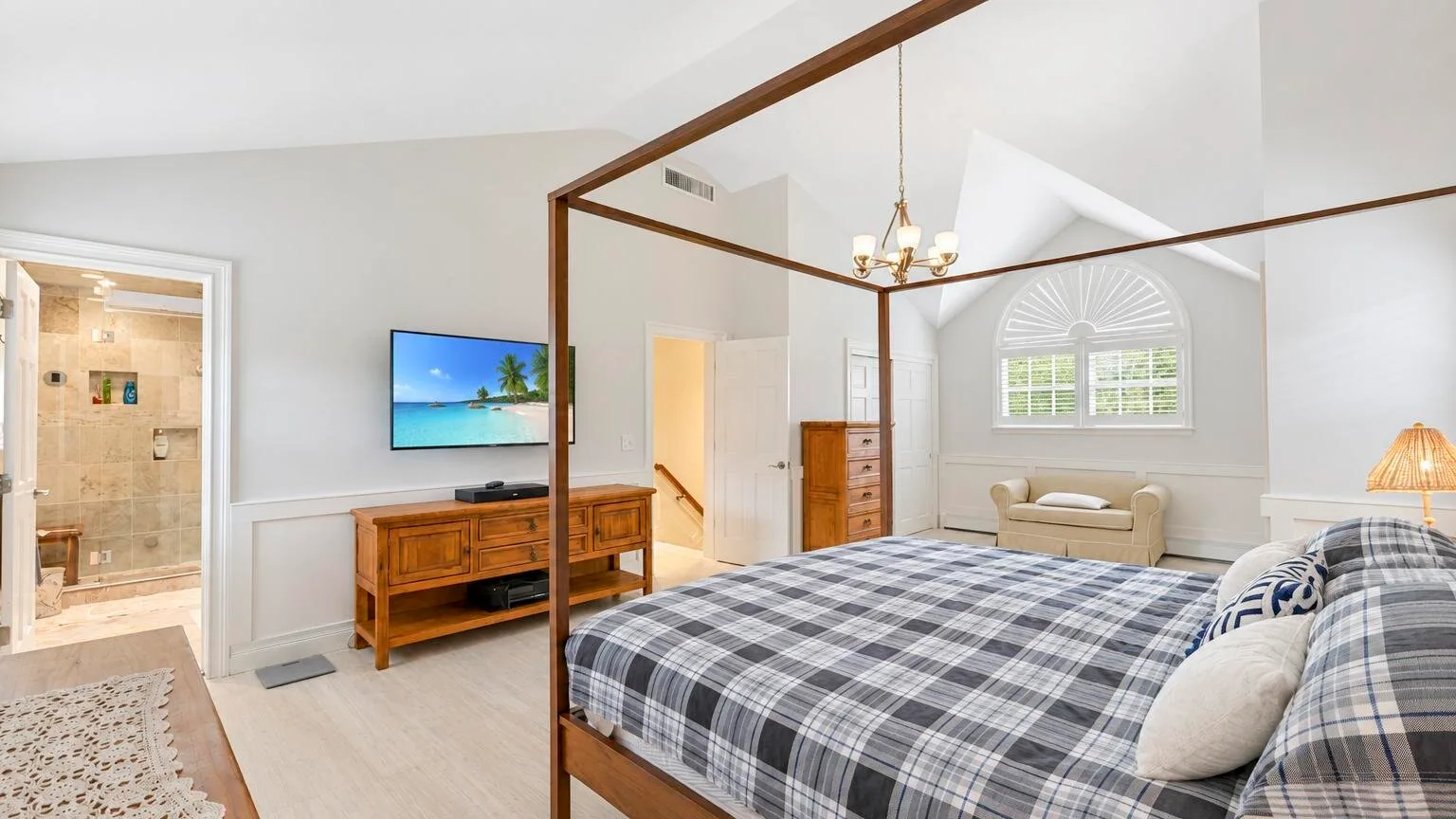 Un dormitorio luminoso con una cama grande, una zona de estar y una entrada al baño.