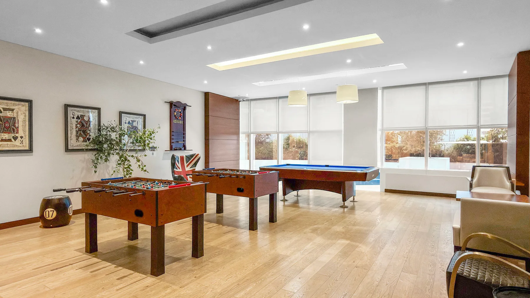 A bright recreation room with two foosball tables and a pool table.