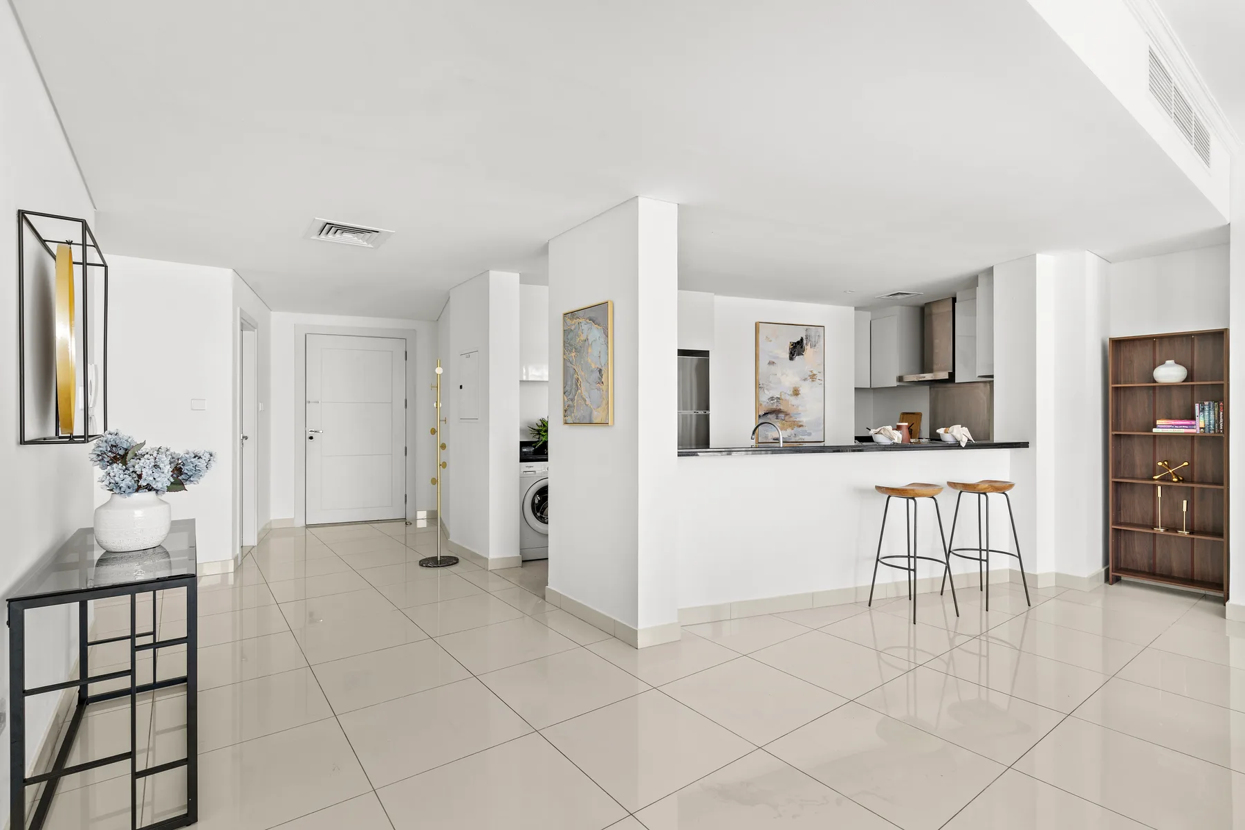 An open-plan kitchen and living area with a breakfast counter and tiled flooring.
