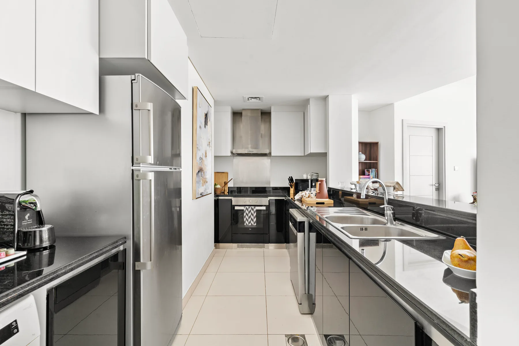 Modern kitchen with dark countertops, stainless steel appliances, and a central sink.