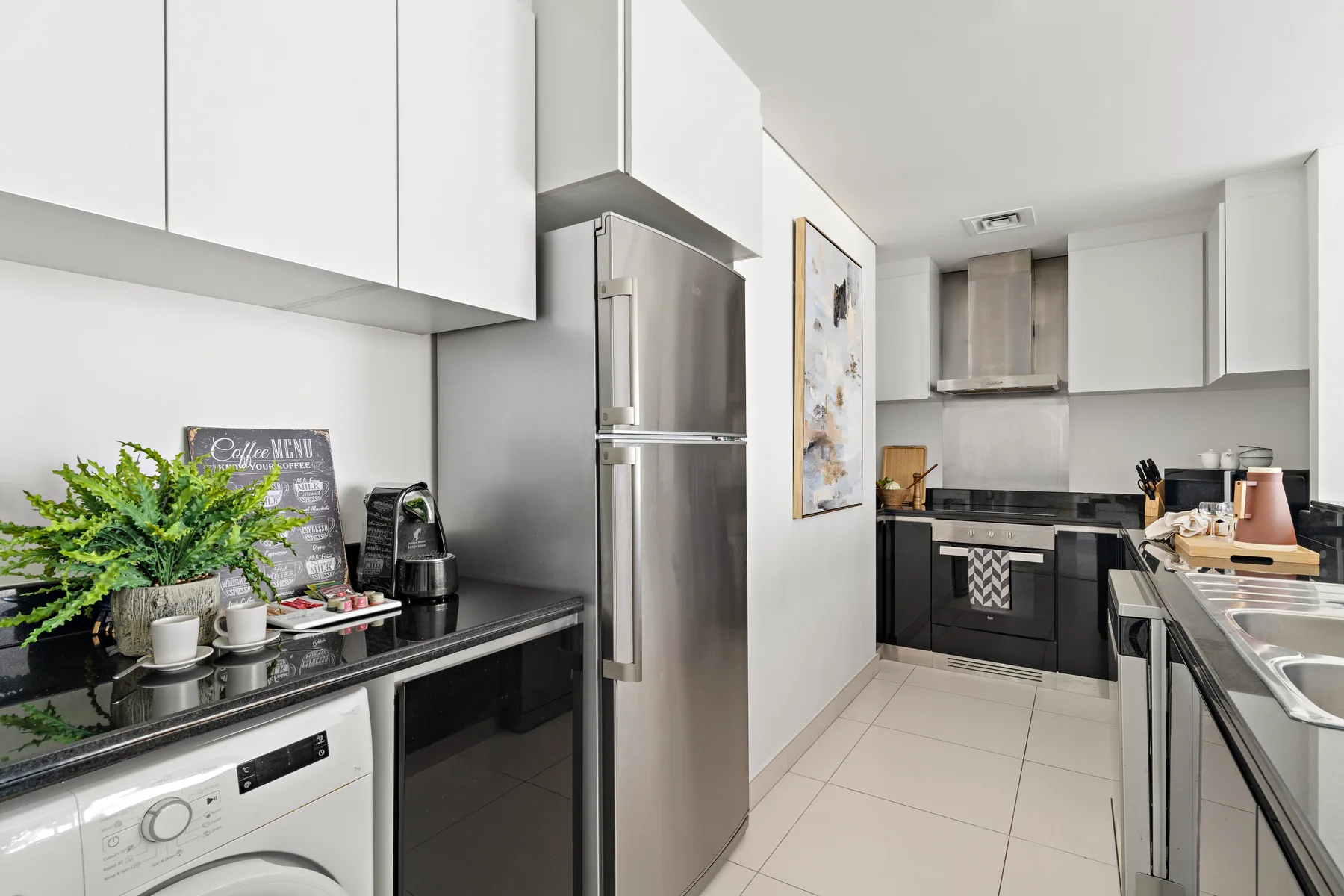 A bright modern kitchen with stainless steel appliances and dark cabinets.