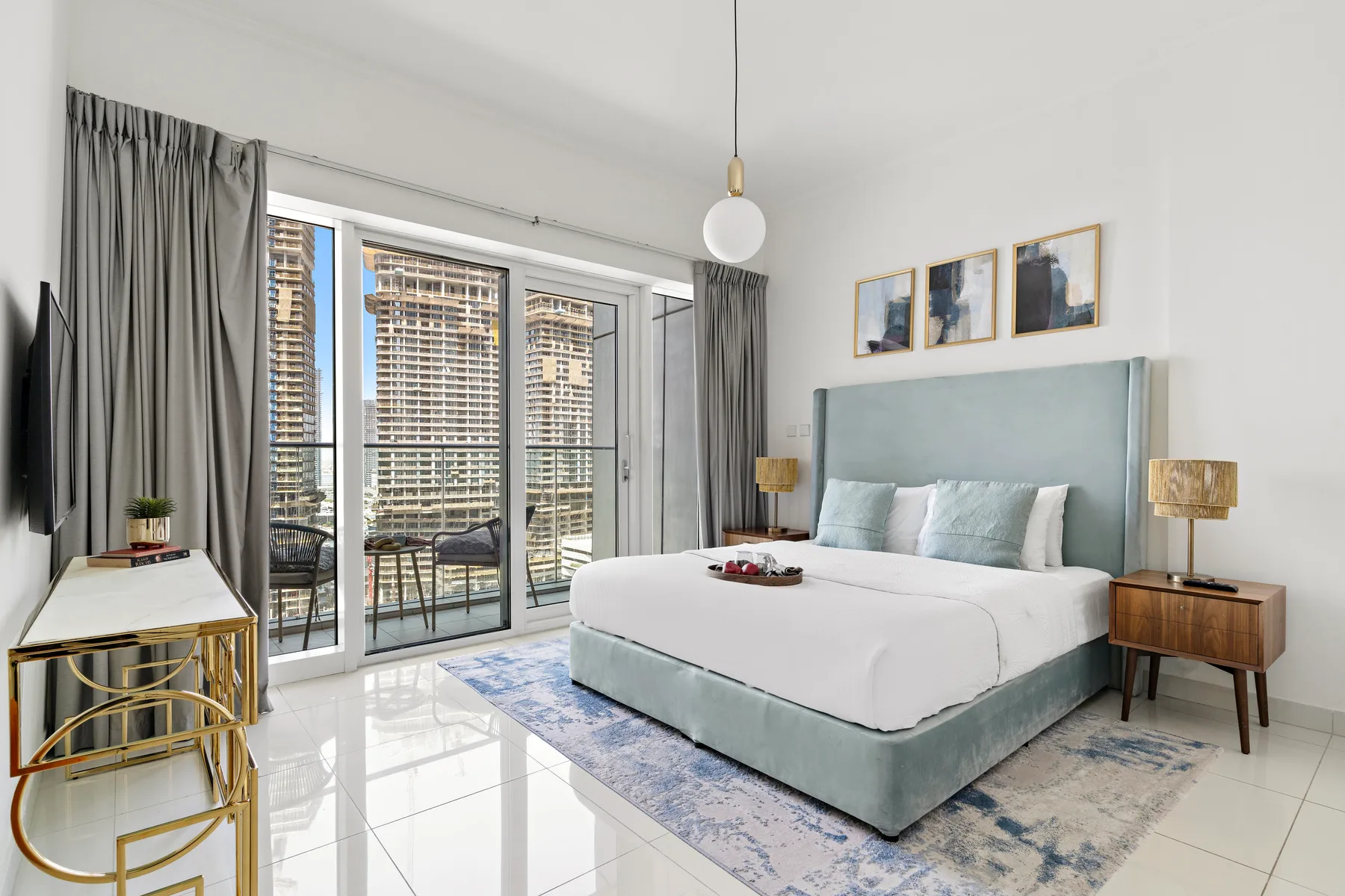 A bright bedroom with a bed, bedside tables, and glass doors opening onto a balcony.