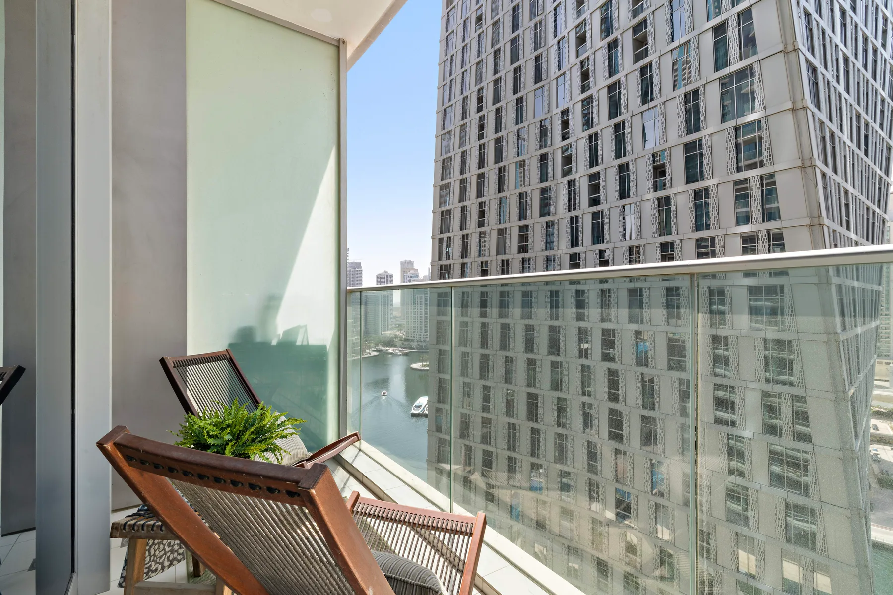 A balcony with reclining seating overlooks nearby high-rise buildings.