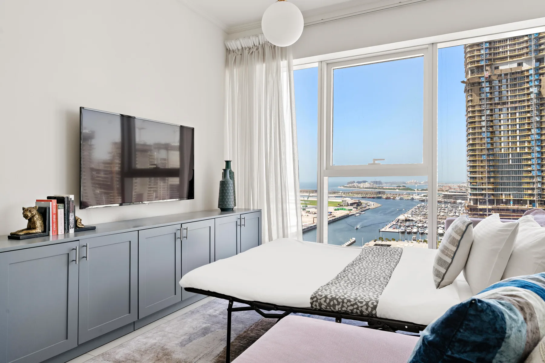 A bright living room with seating beside large windows overlooking a marina.