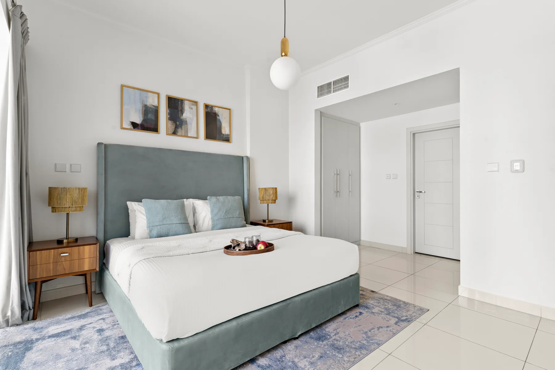 A bedroom with a neatly made bed, bedside tables, and framed pictures above the headboard.