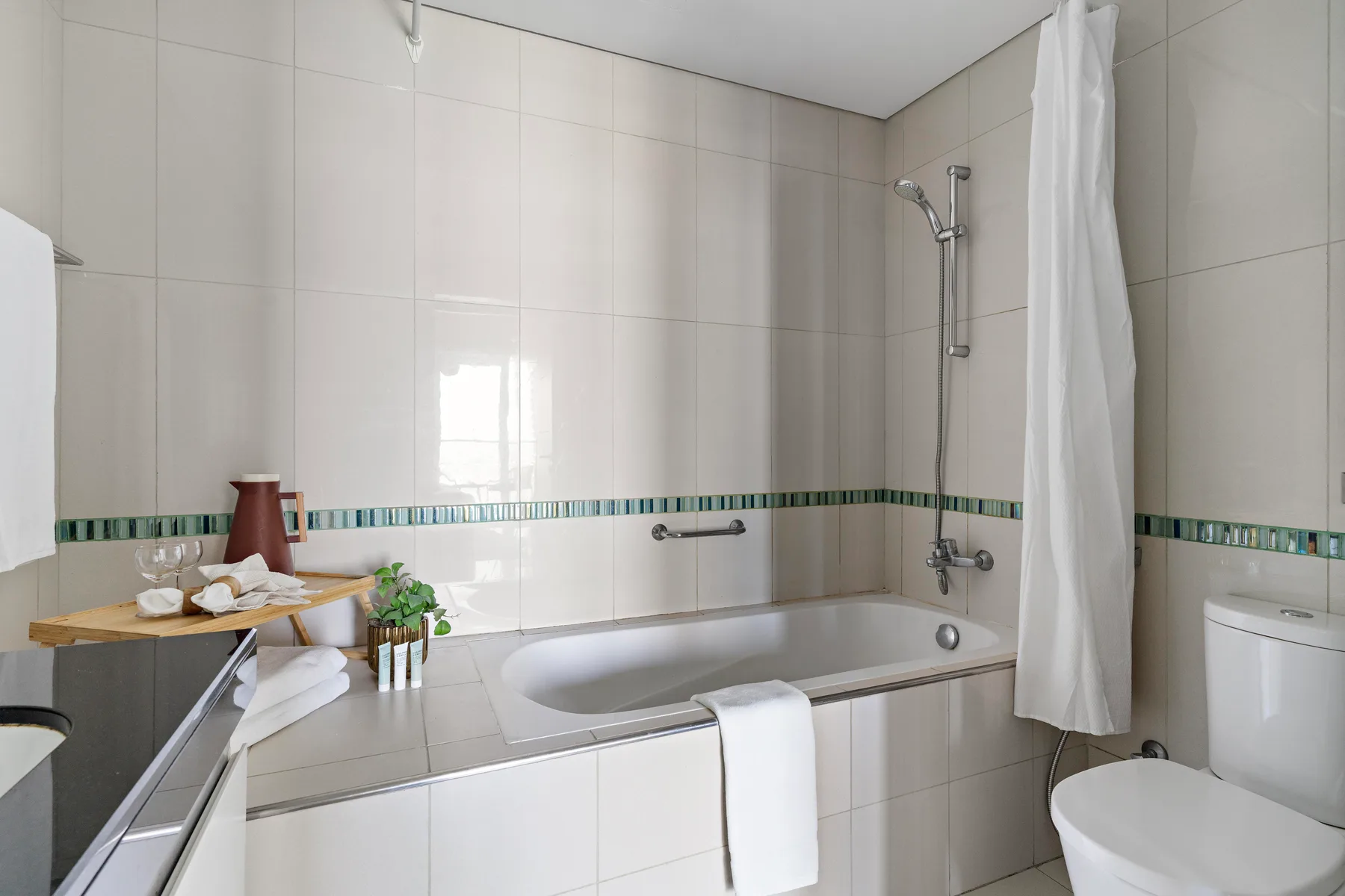 A tiled bathroom with a bathtub, shower, and white curtain.