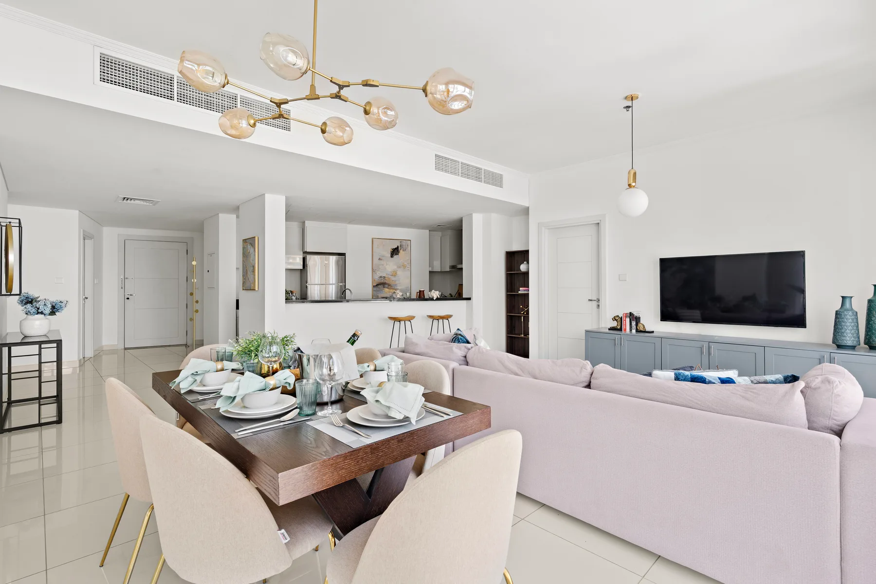 Una luminosa sala-comedor diáfana con la mesa puesta y un televisor.