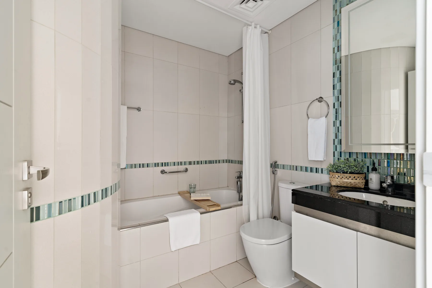 A tiled bathroom with a bathtub, shower curtain, and sink.