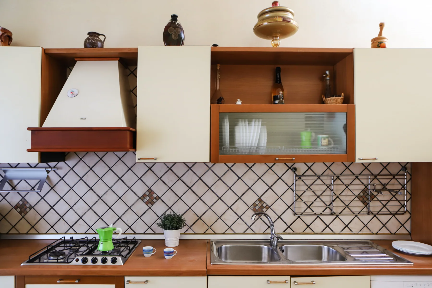A kitchen counter with a stovetop, sink, and patterned backsplash.