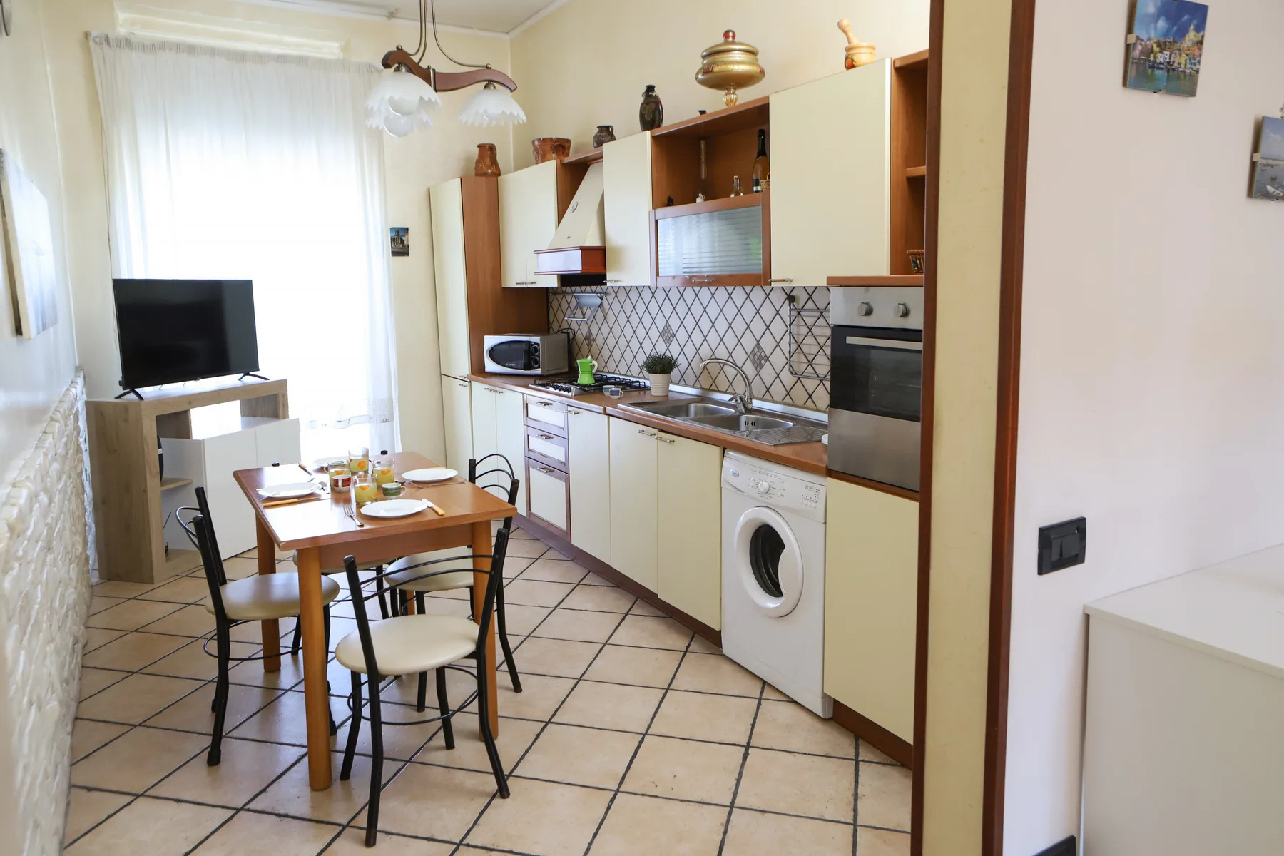 A bright kitchen and dining area with cabinets, a table, and a television.