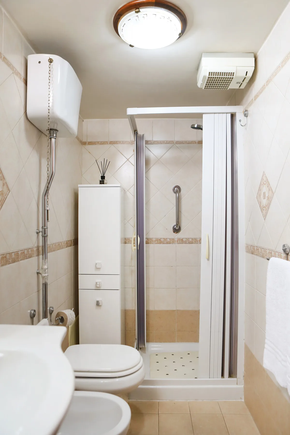 A tiled bathroom with a shower, toilet, and sink.