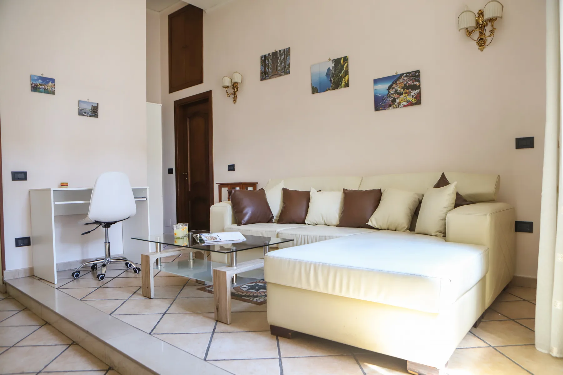 A living room with a cream sectional sofa and a glass coffee table.