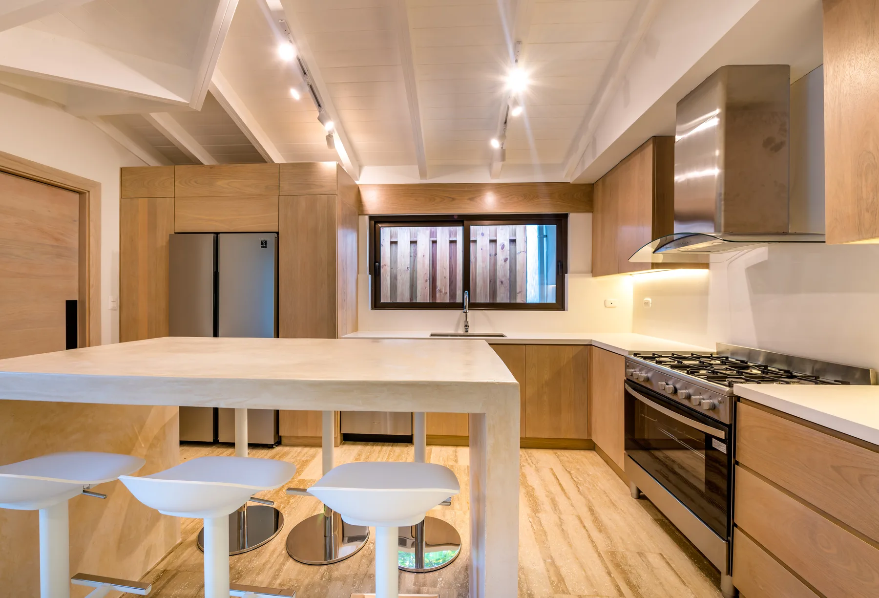 A bright kitchen with a large island, bar seating, and stainless steel appliances.