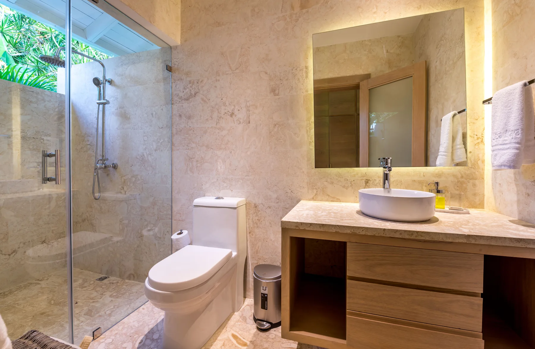 A bathroom with a glass shower, toilet, and vanity.