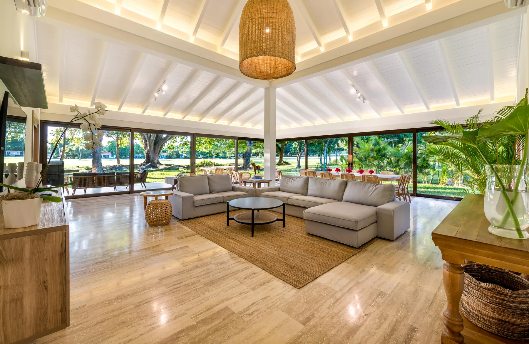 An open living room with seating arranged around a low coffee table and large windows.