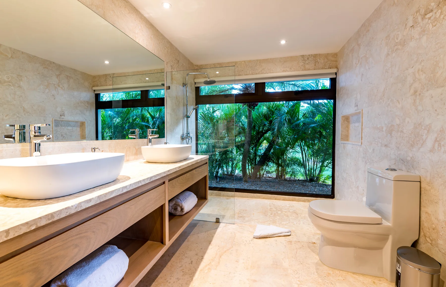 A bright bathroom with a wide vanity, vessel sink, and garden-facing window.