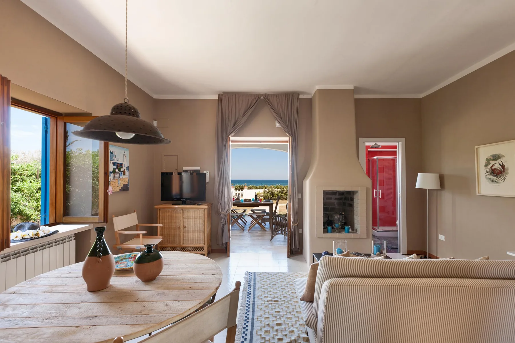A living and dining room opens onto a terrace with a sea view.