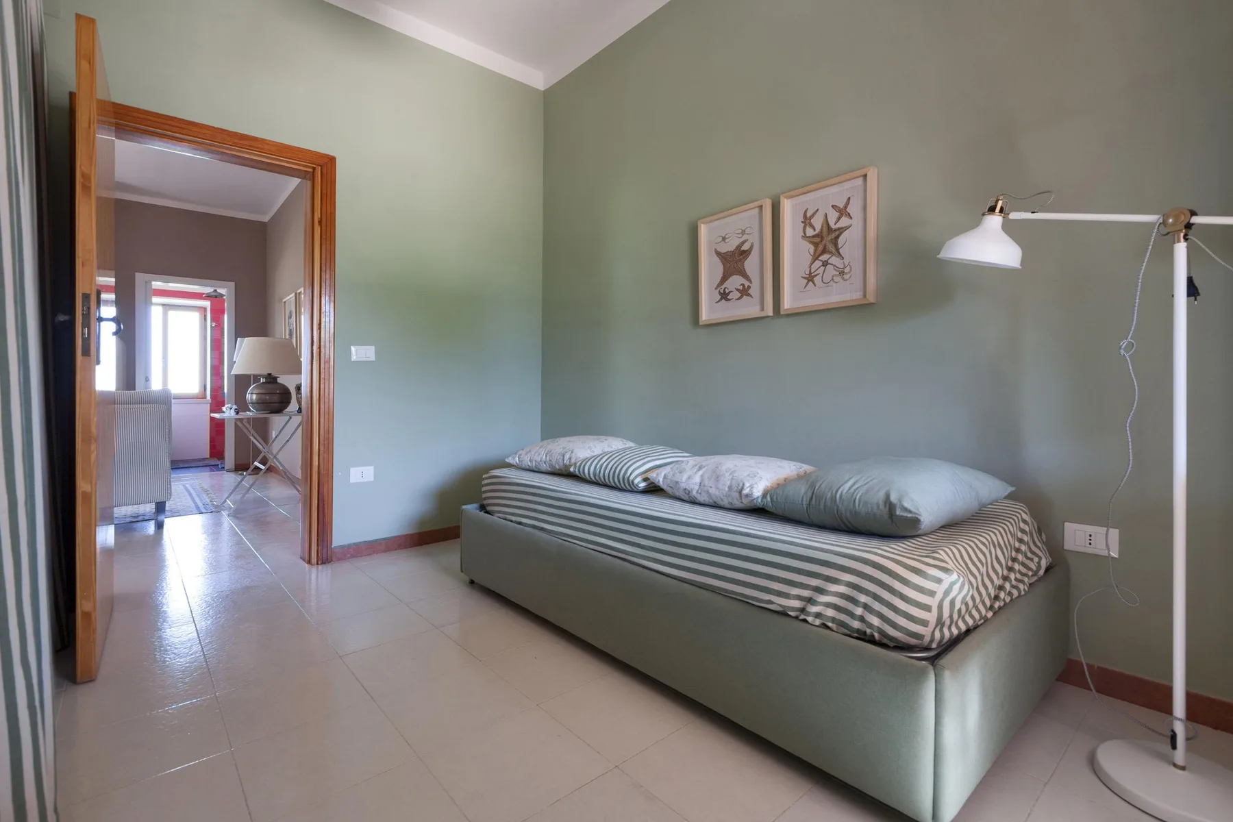 A simple bedroom with a single bed and a floor lamp beside it.