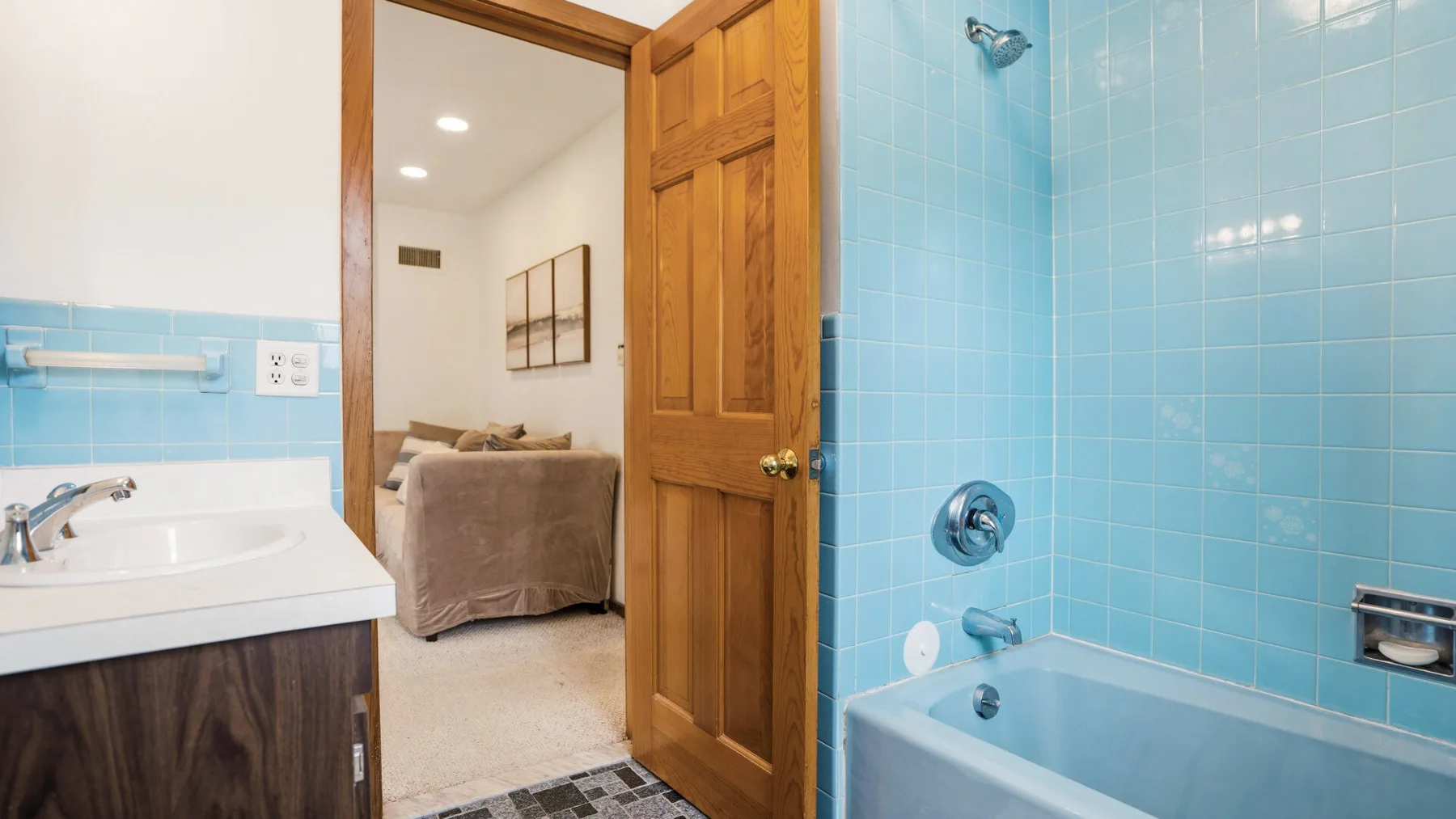 A tiled bathroom with a bathtub, sink, and open wooden door.