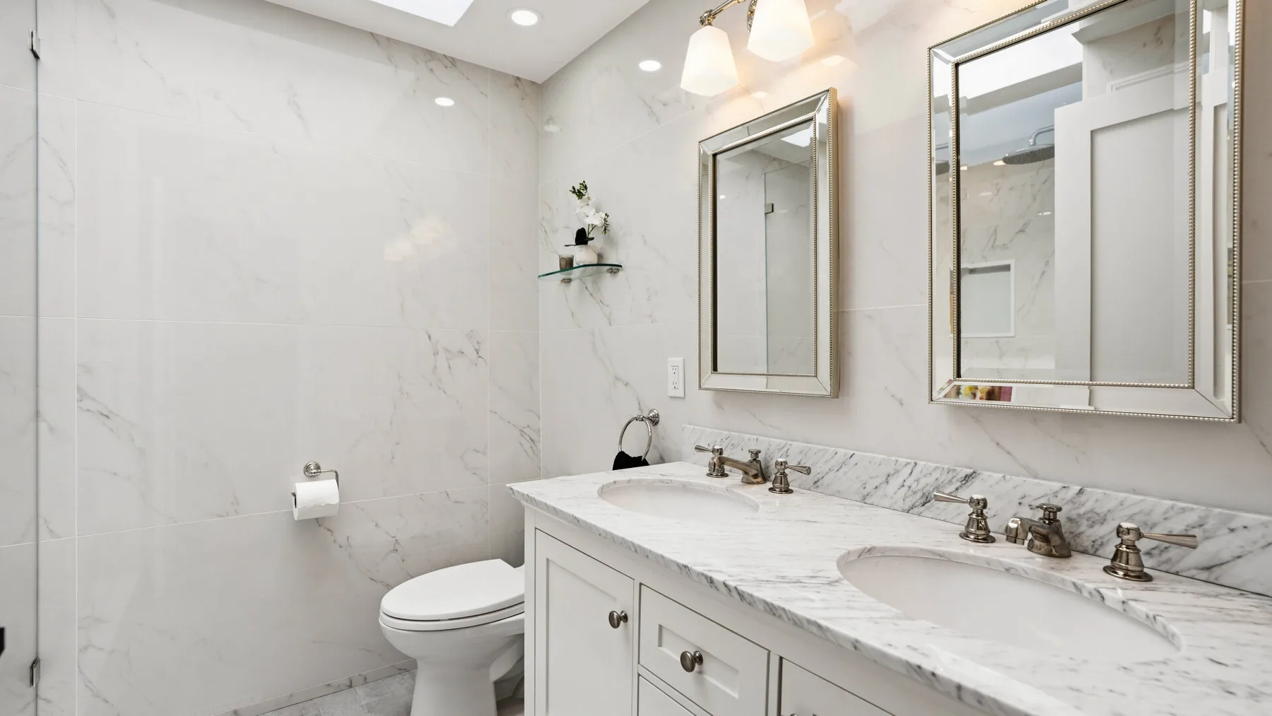 A bright bathroom with a long vanity, two sinks, and a toilet.