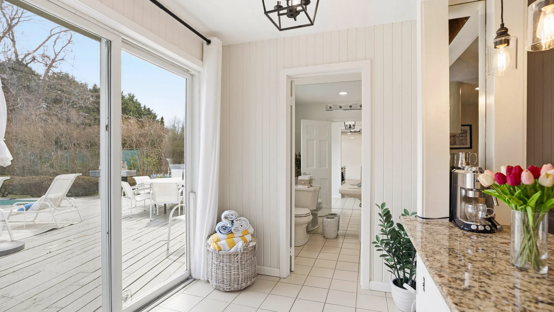 A bright interior opens onto a deck, with a bathroom visible through the doorway.