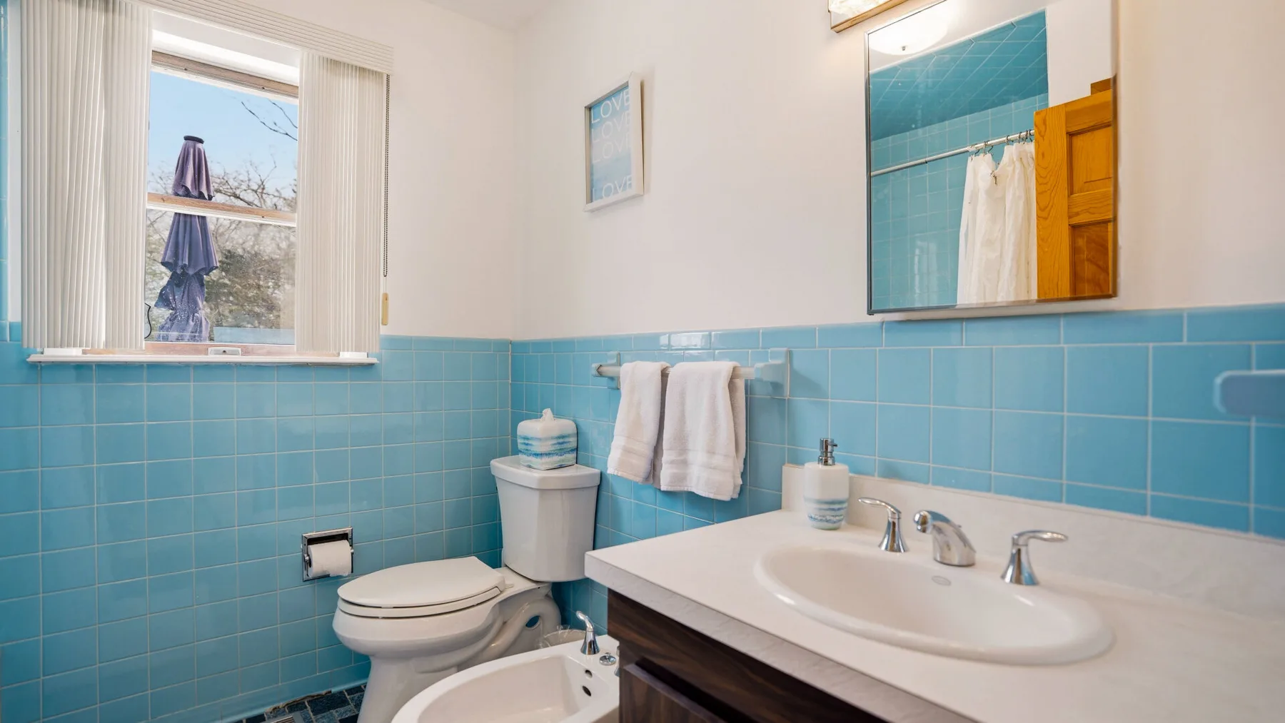 A bathroom with blue tiled walls, a sink, and a toilet.
